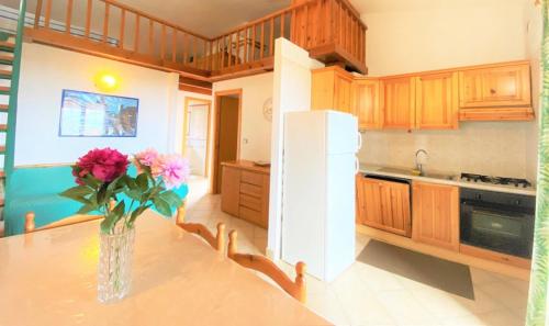 a kitchen with a vase of flowers on a table at SU BISU Costa Rei R4991 terrace with sea view, 500m from the beach in Costa Rei