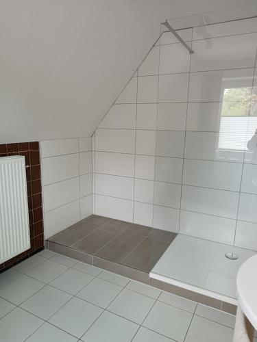 uma casa de banho branca com um chuveiro e um lavatório. em Gästehaus Atrico Haus 7 em Neubörger