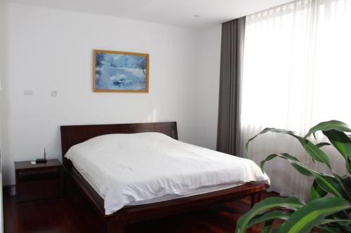 a bedroom with a bed with white sheets and a plant at Davidduc's Apartment 5/41 Tay Ho in Hanoi