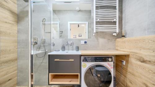 a bathroom with a washing machine and a sink at Apartamenty Sun & Snow Perłowa Przystań in Sianozety