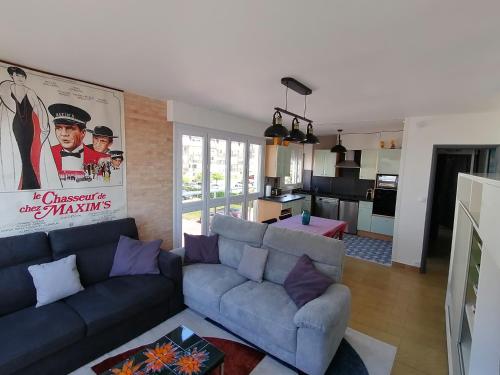 een woonkamer met een blauwe bank en een keuken bij appartement 50 m2 vue mer in Villers-sur-Mer