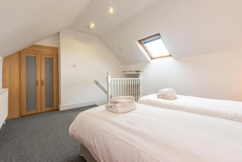 a attic bedroom with two beds and a window at Chesterfield Lodge - 2 Bedroom Apartment near Chesterfield Town Centre in Chesterfield