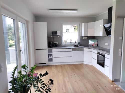 a kitchen with white cabinets and a wooden floor at Ferienapartment 21 in Kurort Gohrisch