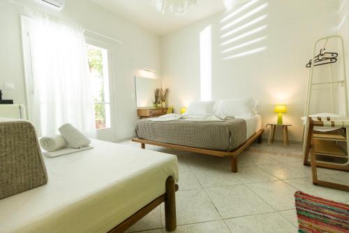a white bedroom with two beds and a window at Mondrian Guest House in Skiathos