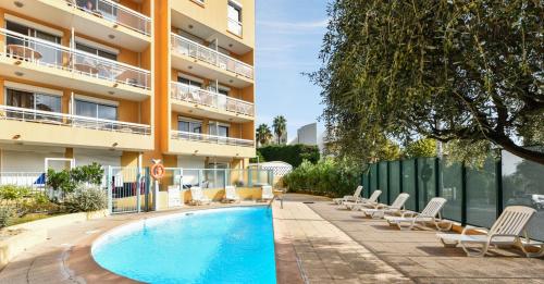a hotel with a swimming pool and chairs next to a building at Résidence Pierre & Vacances La Rostagne in Juan-les-Pins