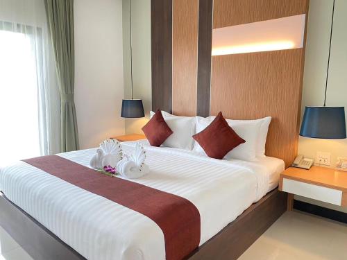 a hotel room with a large white bed with two towels at Siva Royal Hotel in Phatthalung