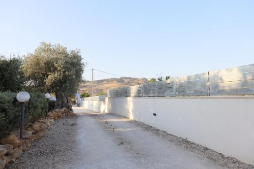 a road next to a white wall next to a fence at Relais Dea Degli Ulivi in Agrigento