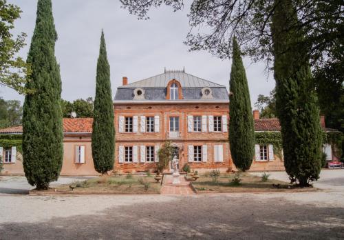 una vieja mansión con árboles delante de ella en Château Lamothe, en Baziège