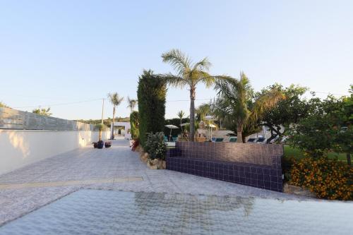 a swimming pool with palm trees and a wall at Relais Dea Degli Ulivi in Agrigento