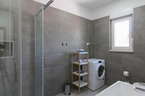 y baño con ducha y lavadora. en Villa Relax II with private pool near the town and the beach by WiiBuk, en Šišan