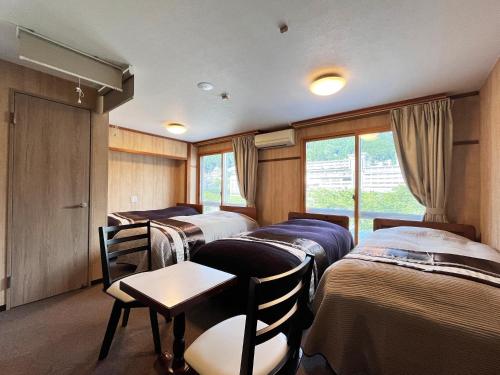 a room with four beds and a table and chairs at Fukiya in Gero