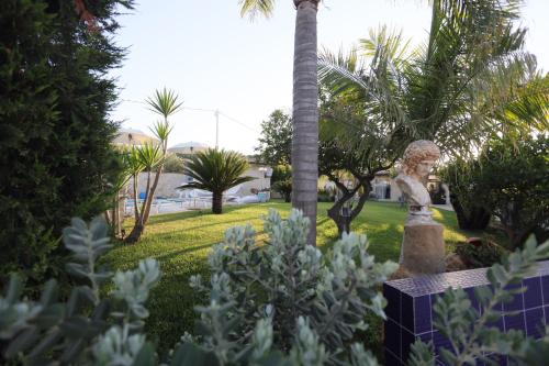 a garden with a statue and palm trees at Relais Dea Degli Ulivi in Agrigento