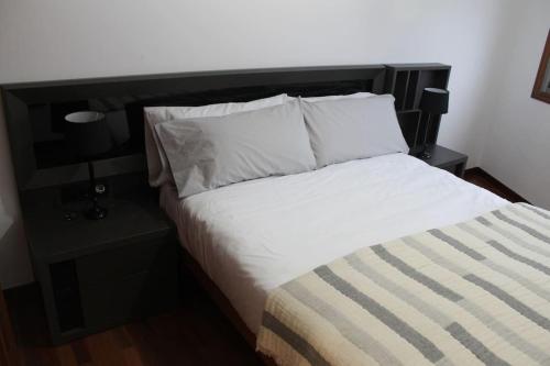 Camino Santiago Inglés Visitar Galicia في Ordes: سرير بشرشف ووسائد بيضاء في الغرفة