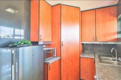 a kitchen with wooden cabinets and a stainless steel refrigerator at Holiday house on the beach in Kingsburgh