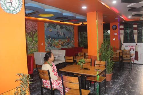 Hotel Giggle Coast Restro and Lodge في Birtamod: امرأة تجلس على طاولة في مطعم