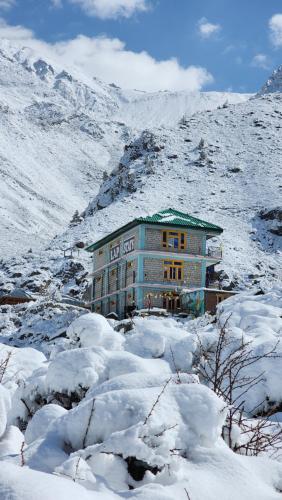 a building on a snow covered hill with a mountain at LAP Stays - Wanderer's Nest in Chitkal