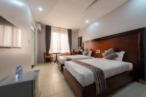 a hotel room with two beds and a table at Las Vegas Garden Hotel Mbarara in Mbarara
