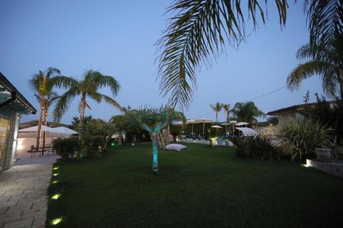 a resort yard with a palm tree and lights at Relais Dea Degli Ulivi in Agrigento