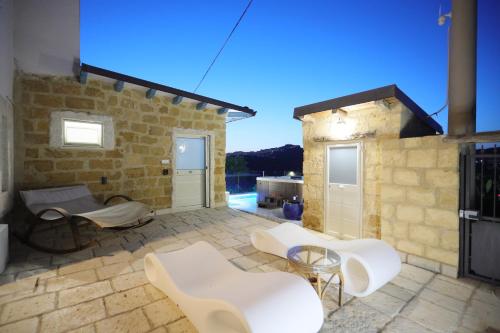 un patio con sedie e tavoli bianchi e un edificio di Relais Dea Degli Ulivi a Agrigento