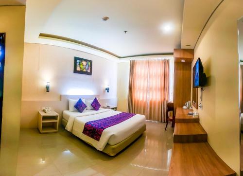 a hotel room with a bed and a television at Grand Madani Hotel in Mataram