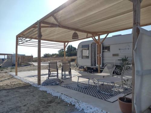 an rv parked under a tent with chairs and tables at Surf Camp Keros in Kalliópi