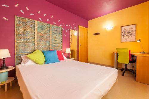 um quarto com uma cama branca e paredes coloridas em La Cantonada em Sant Pere de Ribes