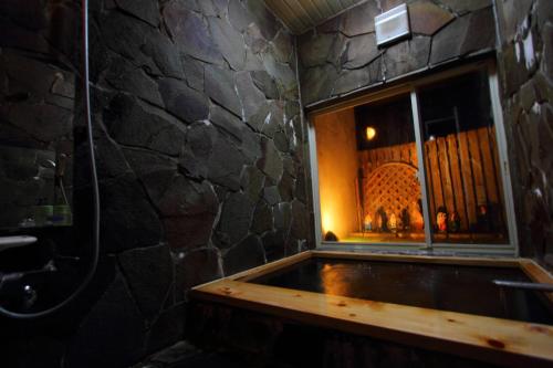 bañera en una habitación con pared de piedra en Scotch Court en Nasu