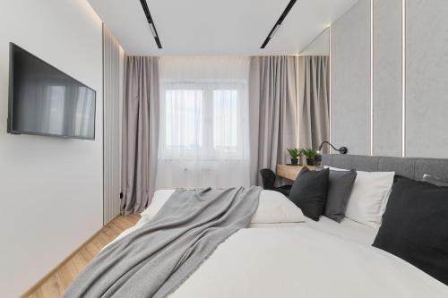 ein Schlafzimmer mit einem Bett und einem TV an der Wand in der Unterkunft Exclusive Apartment with Balcony & Parking Wrocław by Renters Prestige in Breslau