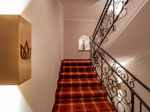 a spiral staircase with a plaid carpet at Alpen Glück Hotel Villa Lisa garni in Kirchberg in Tirol