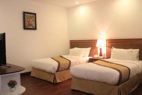 a hotel room with two beds and a television at Phnom Penh Katari Hotel in Phnom Penh