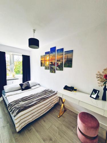 a bedroom with a bed and some paintings on the wall at Apartament Parkowy Mrągowo in Mrągowo