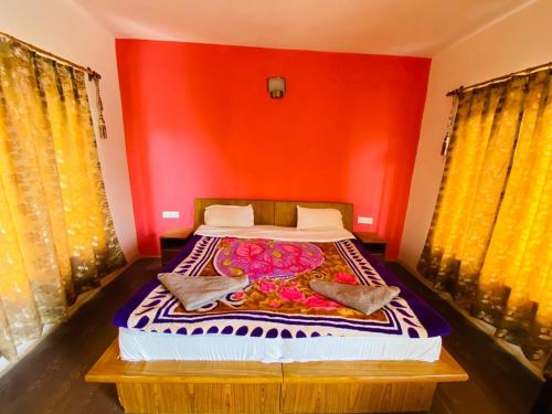 um quarto com uma cama com uma parede vermelha em Mentokling Guest House and Garden Restaurant em Leh