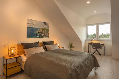 a bedroom with a bed and a desk and two windows at SweetHome - Poing Apartments in Poing