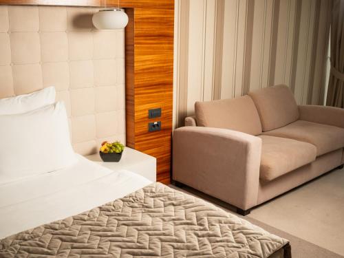 um quarto com uma cama, um sofá e uma cadeira em Garni Hotel Centar em Novi Sad