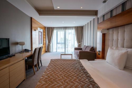ノヴィサドにあるGarni Hotel Centarの大型ベッドとテレビが備わるホテルルームです。