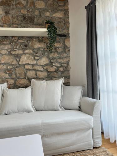 a white couch in a room with a stone wall at Guesthouse 45 in Dutovlje