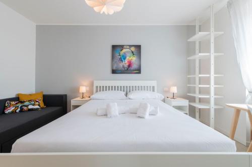 a bedroom with a white bed and a black couch at Casa Maglò camere in Verona