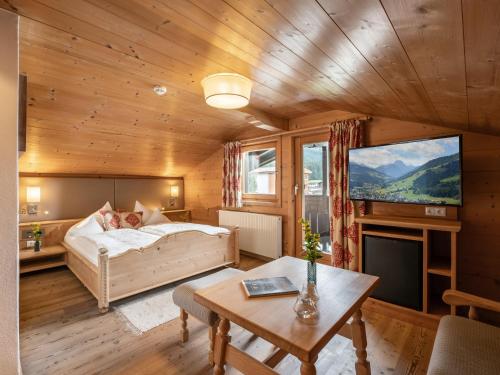 a bedroom with a bed and a tv and a table at Alpen Glück Hotel Villa Lisa garni in Kirchberg in Tirol