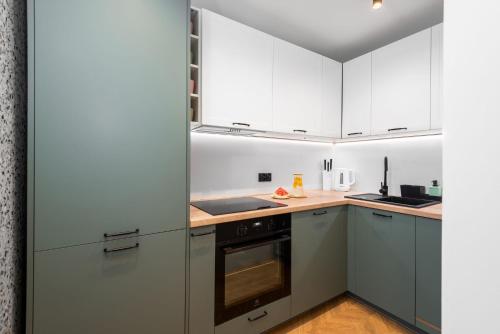 a kitchen with white cabinets and a wooden floor at Kairos Apartments - Diamond - darmowy Parking, ścisłe centrum in Gliwice