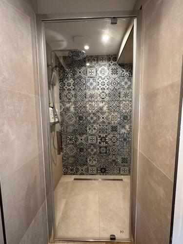 a bathroom with a shower with a tiled wall at La Chapelle de Monet - Logis Les Coquelicots in Bois-Jérôme-Saint-Ouen