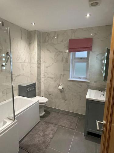 a bathroom with a tub and a toilet and a sink at Modern and cosy 4 bedroom home in the Mendip Hills, North Somerset in Axbridge