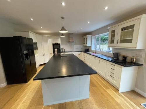 a large kitchen with white cabinets and black counter tops at Modern and cosy 4 bedroom home in the Mendip Hills, North Somerset in Axbridge