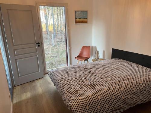 1 dormitorio con cama, puerta y silla en Maison neuve à deux pas du Lac, en Sanguinet