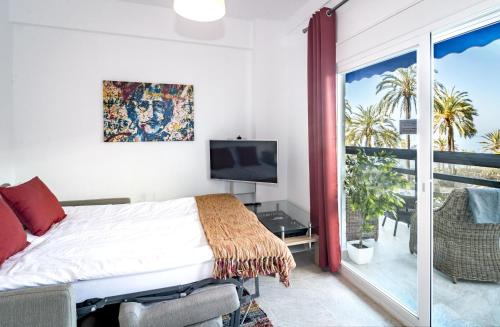 Schlafzimmer mit einem Bett, einem TV und einem Balkon in der Unterkunft Sea promenade apartment in Marbella M27 in Marbella