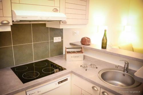 a kitchen with a sink and a bottle of wine at Résidence Goélia La Pommeraie in Branville