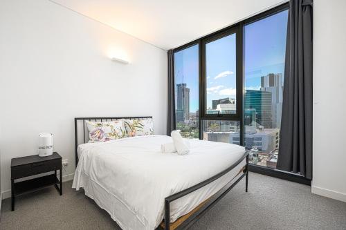 a bedroom with a white bed and a large window at Stunning New 2 Bedrooms Apt Shopping & Parking in Sydney