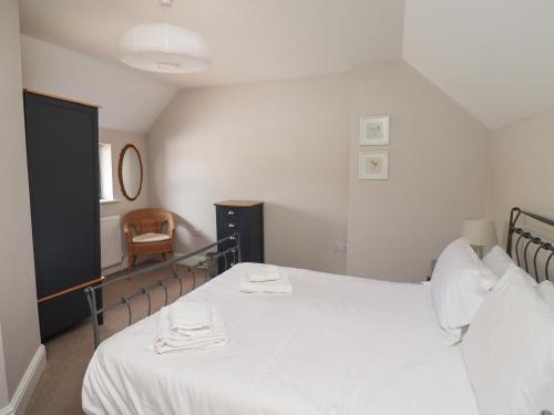 a bedroom with a bed with white sheets and a chair at Riverside Lodge in Alnmouth