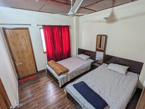 a bedroom with two beds and a window with a red curtain at Mirabazar in Sylhet