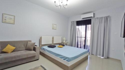 a living room with a bed and a couch at Modern Pool View Studio Apartment in Caesar Resort & SPA, Long Beach in Saint Yeorgios