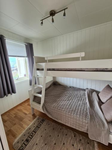 a bedroom with two bunk beds and a window at Aurora apartment in Kvaloya Tromso in Tromsø